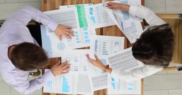 社長と社員は 財務報告書をテーブルに置いています 企業の動向と予測を議論する労働者数とチャートを精査 — ストック動画