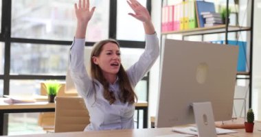 İş kadını işyerindeki bilgisayarın önünde finansal başarıyı kutluyor. Zafer ve başarı duyguları iş başında