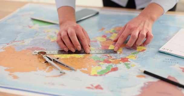 女性は 世界地図上の距離を測定し 定規を使用して旅行を計画します 地図上のパラメータを測定する観光客 — ストック動画