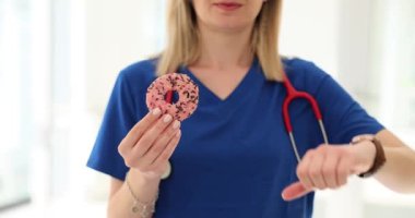 Nutritionist elinde tutuyor ve onaylamayan bir çörek gösteriyor. Tatlıları ve sağlığı bırakmak