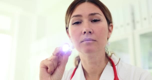 眼科医は患者の目を懐中電灯で検査する フラッシュライト付き神経科医Entと眼科医 — ストック動画