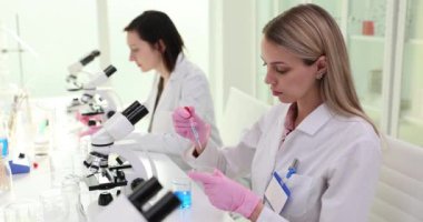 Bilimadamı laboratuvar görüntülerine mikroskop ile petri kabı bırakıyor. Zehirli sıvılar üzerine çalışmalar