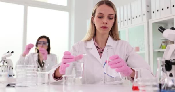 Две Женщины Учёные Работающие Лаборатории Исследуют Прозрачную Жидкость Фляжке Командная — стоковое видео