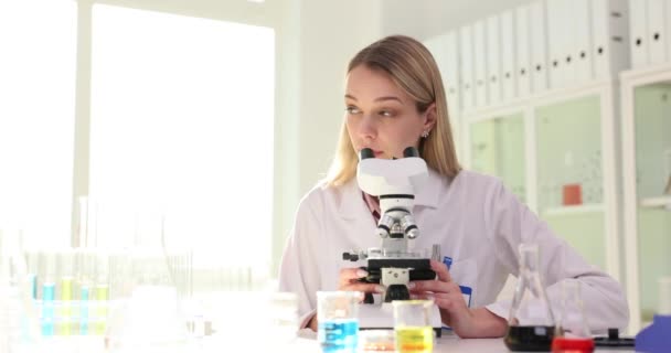 研究室で働く2人の科学者は 顕微鏡の下で液体を分析する 科学医学近代研究所のチームワーク — ストック動画