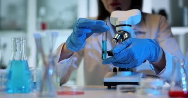 Scientifique Gants Tient Incline Une Éprouvette Avec Liquide Bleu Microscope — Video