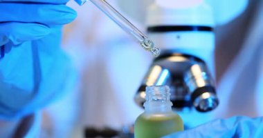 Pipeti ve temiz sıvıyı şişeye koyan bir bilim adamı. Kozmetik yağların laboratuvar testi