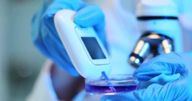 Bir sıvının özgül kütleçekimini ölçmek için dijital refraktometre kullanmak. Bilim adamı DNA örnekleri yüklüyor ve modern genetik laboratuvarında test bandı kullanıyor