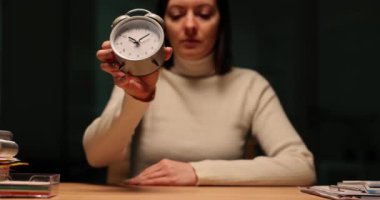Kadın yöneticinin gece ofiste elinde alarmlı bir saat tutması. Çalışma saatleri bitiş saati ve zaman yönetimi