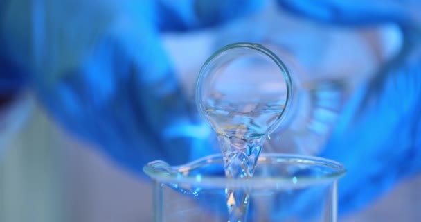 명확한 액체는 실험실에 유리제 비커로 유리제 비커에서 부어집니다 과학자 연구원에 — 비디오