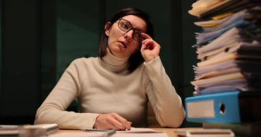 Yorgun ofis çalışanı gece ofiste evrak işleriyle çok meşgul oluyor. Muhasebeci gözlüklerini çıkarıp gergin ve depresif görünüyor.