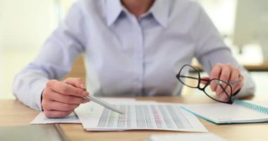 Kadın ofisteki belgelerde finansal veri tablolarını analiz ediyor. İş analizi ve muhasebe raporu