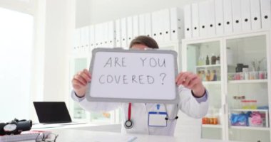 Pratisyen hekim klinikte sigortanız olup olmadığını soruyor. Kağıt çizelgeleri olan hemşire gönüllü sağlık sigortanız var mı?