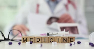 Doktor masasında kelime şırıngaları ve ilaç var. Doktor röntgen görüntüsünü inceler ve iç organların ultrasonunu inceler.