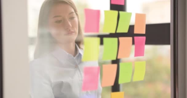 Thoughtful Businesswoman Looks Colored Stickers Glass Wall Thinks Business Ideas — Stock Video