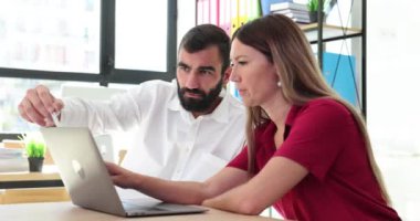 İş ortaklarından oluşan bir ekip, erkek ve bir kadın masada oturur ve laptopta başarılı projelerini tartışır. Profesyonel hedef odaklı iş arkadaşları birlikte çalışıyor