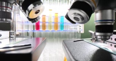 Bir sürü mikroskop ve renkli sıvılarla dolu test tüpleri bir kimya laboratuvarında bir masanın üzerinde. Zehirli sıvıların modern laboratuvar ve kimyasal araştırmaları