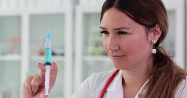 Kadın doktor elinde mavi sıvıyla bir şırınga tutuyor. Kozmetik güzellik enjeksiyonları veya aşılar