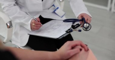 Doktor ve hasta muayene oluyor ve hasta dosyasına yazıyor. Hasta tıbbi belgelerini dolduruyorum.