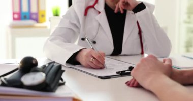 Kadın doktor elleri hasta kayıt formunu dolduruyor. Klinikteki bir hastanın tıbbi evraklarını dolduruyorum.
