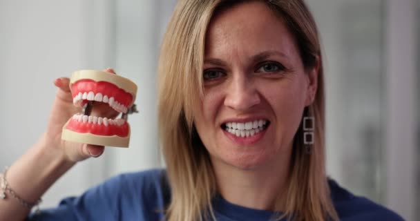 여자는 미소와 여성은 건강한 치아와 플라스틱 모델을 비교하고 완벽한 치아를 — 비디오