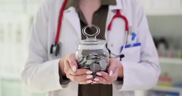 Kobieta Lekarz Trzyma Słoik Monet Klinice Ubezpieczenie Zdrowotne Oszczędności — Wideo stockowe