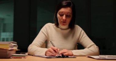 Kadın ofisteki masada karanlıkta yazıyor. Eğitim ve gece fazla mesai