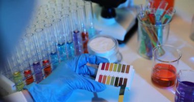 Laboratuvar teknisyeni kağıt üzerinde renk paleti karşılaştırma kalıpları kullanır. Eldivenlerdeki kimyager orijinal örnekteki bileşenleri tanımlar