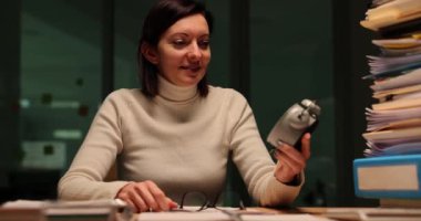 Kadın işçi şirket ofisinde eski saatleri yavaş çekimde kontrol ediyor. Neşeli bayan iş gününün bittiğinin farkına varır ve çabucak ofisten çıkar.