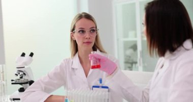 İki bilimadamı bir laboratuarda birlikte çalışıyorlar ve kırmızı sıvının nahoş kokusunu alıyorlar. Başarısız kimyasal deney ve ekip çalışması