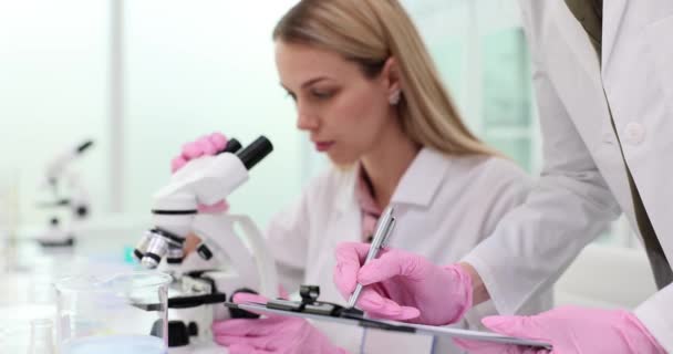 Femme Scientifique Utilise Microscope Prend Des Notes Travail Collaboratif Des Vidéo De Stock