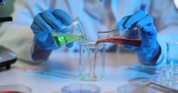 Scientist Carefully Mixing Green Red Liquids Glass Beaker Scientist Working — стоковое видео