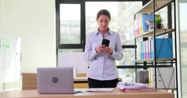 Yeni fikirleri düşünen düşünceli bir iş kadını akıllı telefona ve yüz masasına bakar. Gadget bağımlılığı