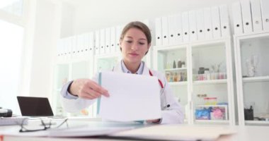 Genç bayan doktor, klinikteki hastaların tıbbi kayıtlarını ve test sonuçlarını inceliyor. Tıbbi raporlar inceleniyor