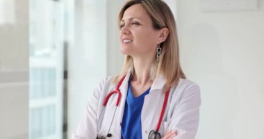 Kendine güvenen beyaz önlüklü kadın doktor kameraya gülümsüyor. Yetenekli bir doktorun başarılı kariyeri.