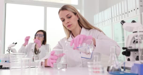 两名科学家正在进行一项实验室实验 检查水质 化验室的化学家把一种透明的溶剂倒入瓶中 — 图库视频影像
