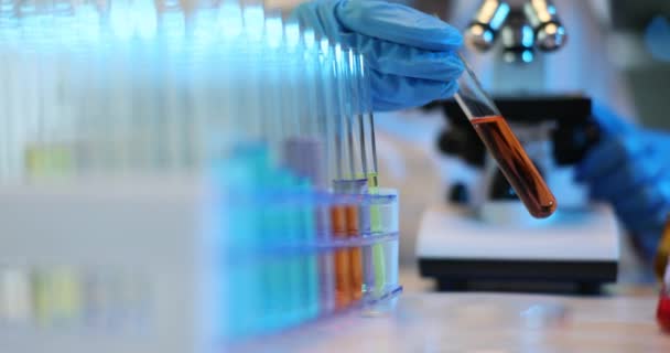 科学家拿着装有橙色液体的试管进行分析 实验室中有毒溶剂的研究 — 图库视频影像