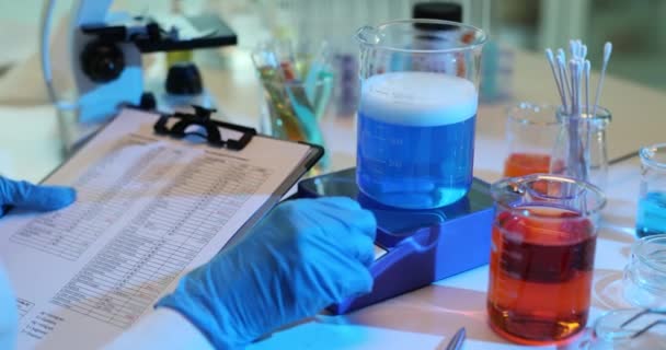 Cientista Mistura Líquido Azul Laboratório Escreve Relatório Experimento Químico Com — Vídeo de Stock