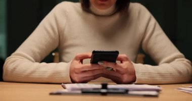 Kadın gece geç saatlerde iş yerinde telefon kullanıyor. Müşteri ile gece ya da akşam yazışmaları ve fazla mesai