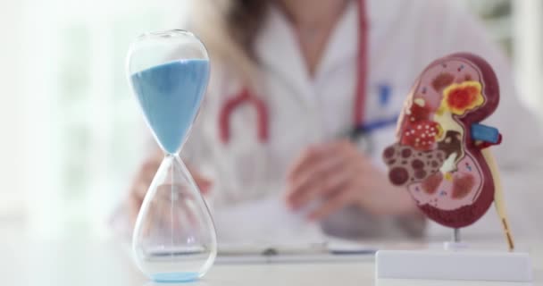 Arzt Macht Notizen Über Nierenerkrankungen Des Patienten Und Eine Sanduhr — Stockvideo