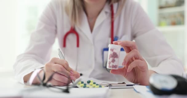 セラピスト医師は丸薬の瓶を保持し 患者に処方箋を書いています 薬の選択と病気のための薬の選択 — ストック動画