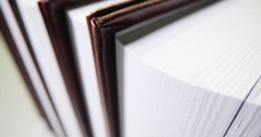 Kitap rafında titizlikle düzenlenmiş kitaplar duruyor. Çarpıcı kapaklı kitaplar ve benzersiz tasarımlar mükemmel bir şekilde yavaş çekimde yerleştirilmiş.
