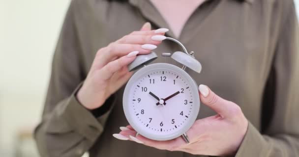 女性は毎日のルーチンの重要性を強調するスタイリッシュな目覚まし時計を保持しています 女性は成功のための効果的な時間管理の本質を反映しています — ストック動画