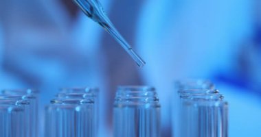 Laboratuvar çalışanı cam pipet kullanarak yavaş çekimde kaynama tüplerine reaktör bırakıyor. Kimyager laboratuarda deney hazırlığı yapıyor.