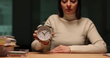 Yorgun kadın, eski çalar saatin akşam olduğunu gösteriyor. Yorgun iş kadını iş sorumluluklarından dinlenmek ve gençleşmek istiyor.