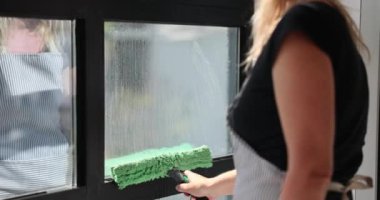 Ev hanımı camları köpük kazıyıcı ile temizler. Pencere Temizleme Servisi