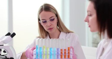 Laboratuvardaki iki bilimadamı deney tüpleri üzerinde deney yapıyorlar. Kimyagerler test tüplerindeki renkli sıvıları inceliyor.
