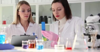 İki bilim adamı laboratuarda petrol ürünlerini test ediyorlar. Bilim adamları ve kimyagerler sarı sıvıyı camda test ediyorlar.