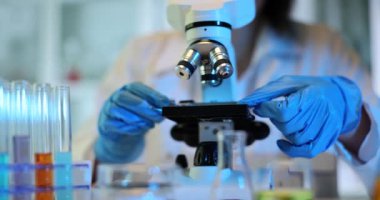 Modern laboratuvar ekipmanları kullanılarak yeni malzemelerin mikroskobik analizi. Bilim adamı mikroskopta cam kaydırağı kuruyor.