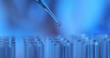 Laboratuvardaki test tüpüne mavi sıvı pipetler damlatın. Laboratuvarda alkol ve çözücü araştırması
