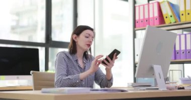 Tired female employee answers the phone and sleeps at office desk. Fatigue overwork and overtime work in office